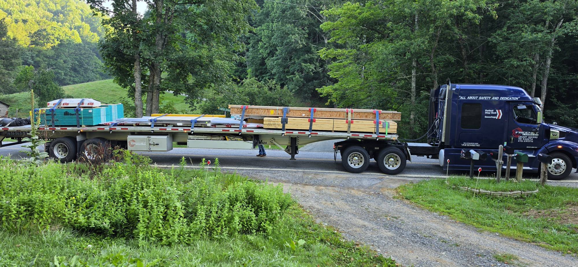 Flatbed truck carrying the kit arrives on a rural road