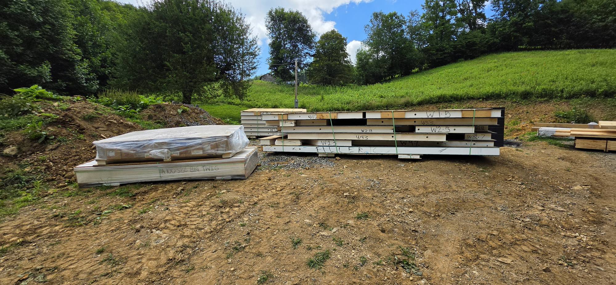 SIP panels and lumber staged on the site after offloading