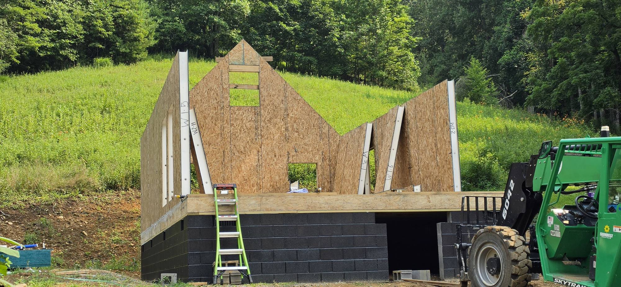 First SIP wall panels standing on the deck with a telehandler alongside
